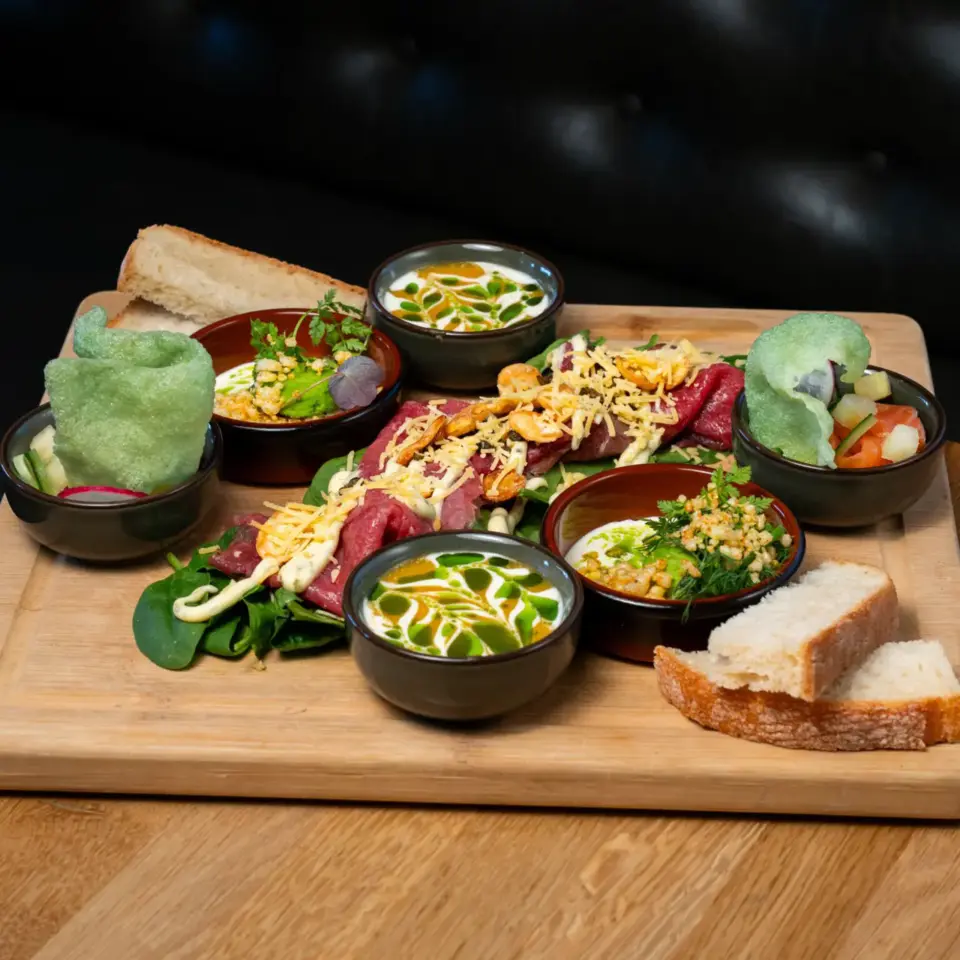 Verschillende kleurrijke lunchgerechten op een houten plank op een tafel bij restaurant Bar Dixie in Amstelveen﻿